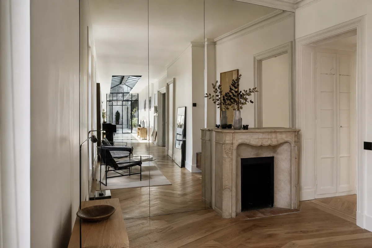 Grand mur de miroirs du sol au plafond dans un séjour haussmannien parisien étroit baigné de lumière
