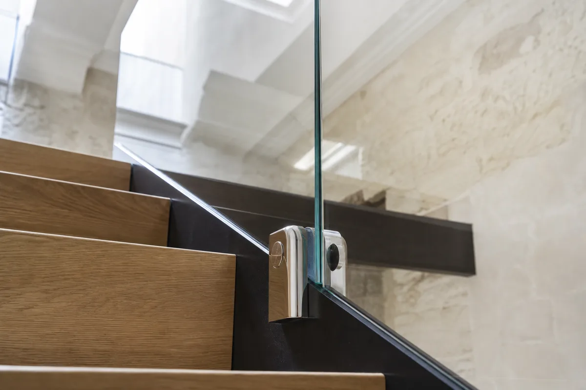 Garde-corps d&rsquo;escalier en verre feuilleté fixé par pinces inox dans une cage d&rsquo;escalier parisienne